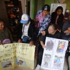 Las dos familias de los 11 migrantes muestran los carteles con las fotos de sus seres queridos.