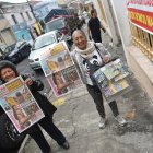 Dos voceadores  muestran con alegría el Diario EXTRA que venden todos los días en Quito.