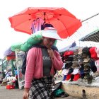 Nancy lleva las compras en su espalda hasta la cajuela de un vehículo.