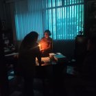 Con luz de velas, la notaria leyó documentos para firmarlos.