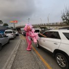 El personaje recorre la acera a un paso peculiar y saludando a los viajeros, muchos de los cuales se han vuelto sus clientes por la vistoso de su atuendo.