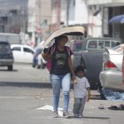 Una mujer usó un cartón para taparse del sol mientras caminaba con una niña.