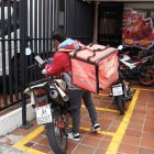 Los repartidores esperan por los pedidos en las aceras o en parques.