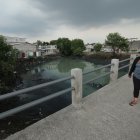 Una mujer se tapa la nariz y apura el paso al cruzar por un puente sobre el estero Salado, en el suburbio porteño.