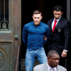 El peleador de artes marciales mixtas, el irlandés Conor McGregor (i), es escoltado mientars abandona una comisaria neoyorquina