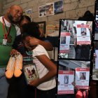 Luis Arroyo y Katty Bustos, abrazados a su hija menor, sostienen entre sus manos los zapatos de Ismael y Josué, sus dos hijos desaparecidos.