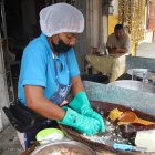 Doña Gaby usa una paila de madera para majar el verde y mezclarlo .