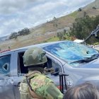Un militar retira los restos del parabrisas tras el ataque a la caravana presidencial en Cañar.
