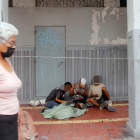 Grupo de personas prepara y usa sustancias a plena vista, mientras los transeúntes siguen de largo.