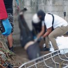 Agentes de la Policía y del Cuerpo de Bomberos extraen un cuerpo de la cisterna ubicada en el barrio Vista al Mar, dentro de una escuela abandonada.