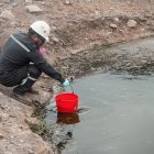 Una persona recoge el agua contaminada del río Daule.