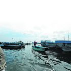 Un hombre se abre paso entre las embarcaciones pesqueras. En el puerto no funciona el retén naval.