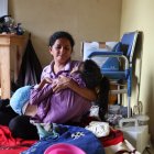 Mayra Canales sostiene a su hija, en el interior de su vivienda en Bastión Popular.