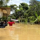 Dos personas avanzan con dificultad entre aguas turbias que cubren gran parte de la comunidad de San Gregorio, mientras viviendas y cultivos permanecen bajo el nivel de la inundación.