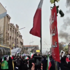Manifestantes marchan en Teherán mientras humo de una explosión se observa a lo lejos