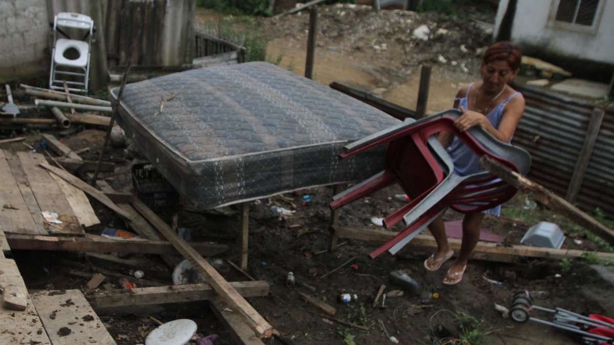 Guillermina intenta limpiar los escombros que quedaron de su casa.