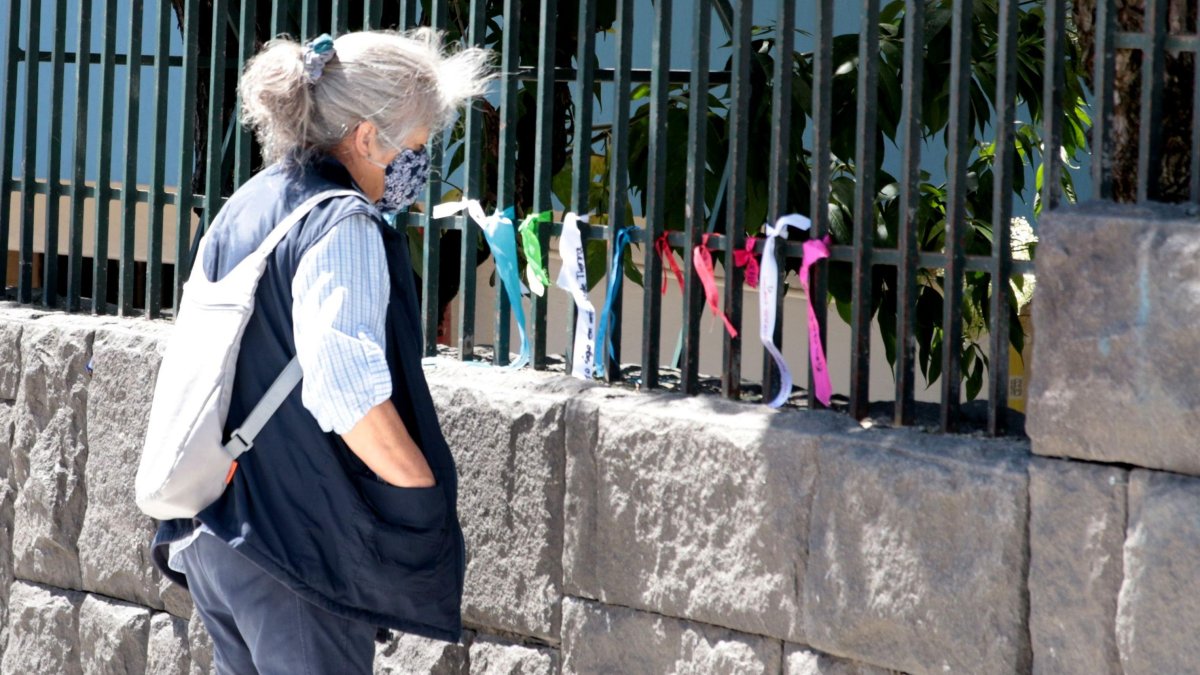Algunos familiares que esperan noticias de sus parientes en las afueras del hospital se dan una vuelta por las rejas donde están los lazos.