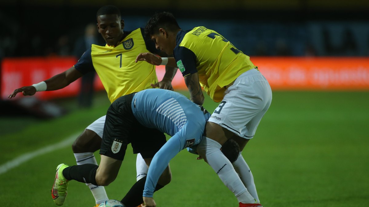 Agustín Álvarez de Uruguay disputa el balón con Pervis Estupiñán (i) y Piero Hincapie (d) de Ecuador.