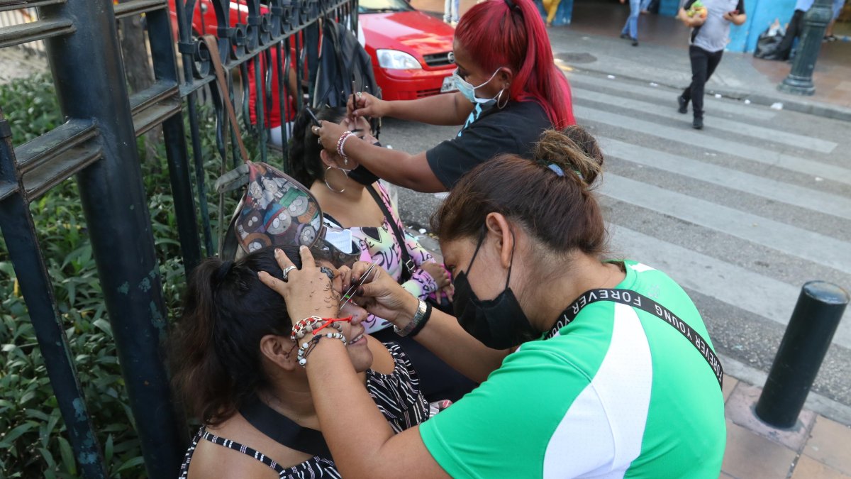 Las mujeres atienden a las usuarias en el bordillo del parterre central de la avenida Olmedo, en la esquina de Chile.