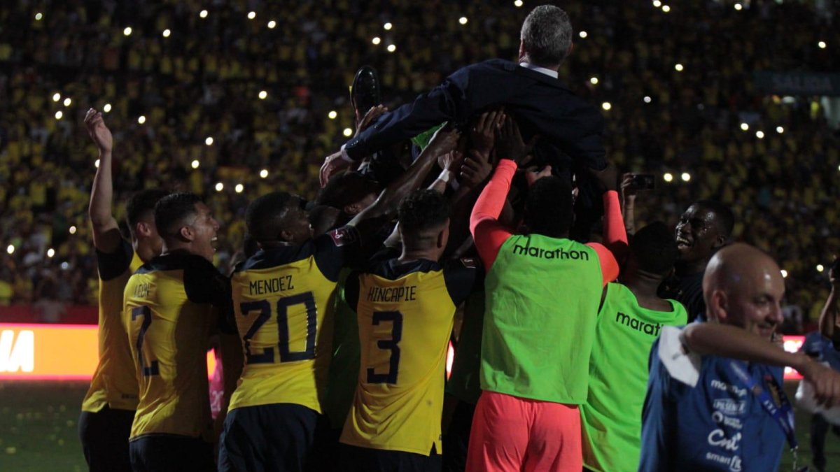 Gustavo Alfaro levantado por los jugadores de Ecuador.