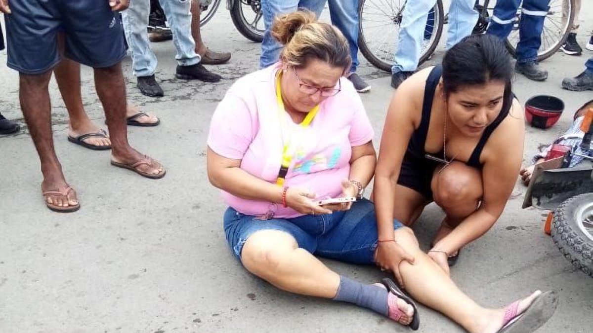 La esposa del acribillado junto a otro familiar lloran junto a la moto.