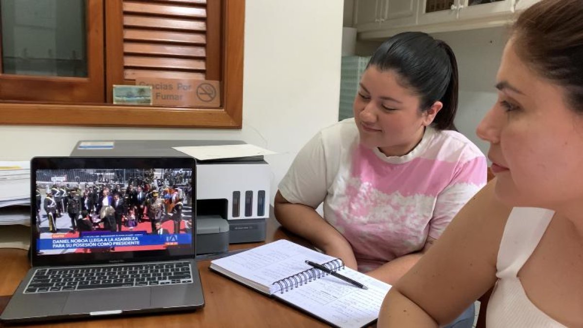 Geanella Altamarino (i) junto a su colaboradora Maitte Medina (d), observando la ceremonia en su laptop, en una oficina del negocio.