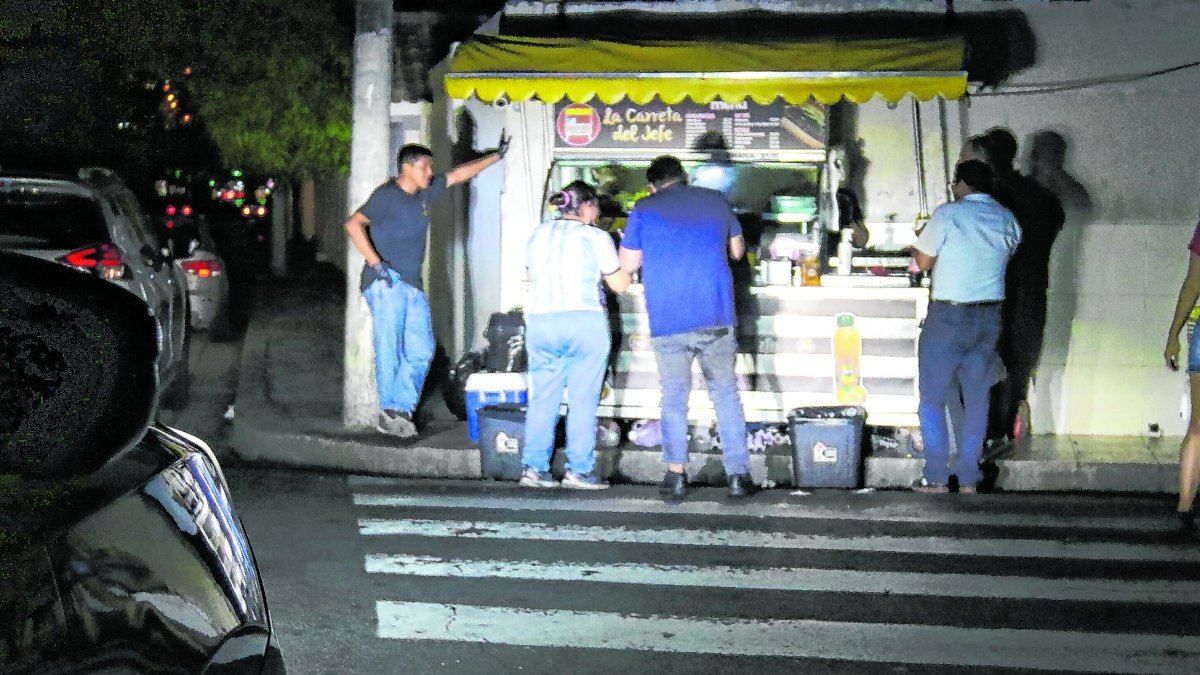 Una carreta usa la luz de una camioneta para alumbrar a sus clientes.