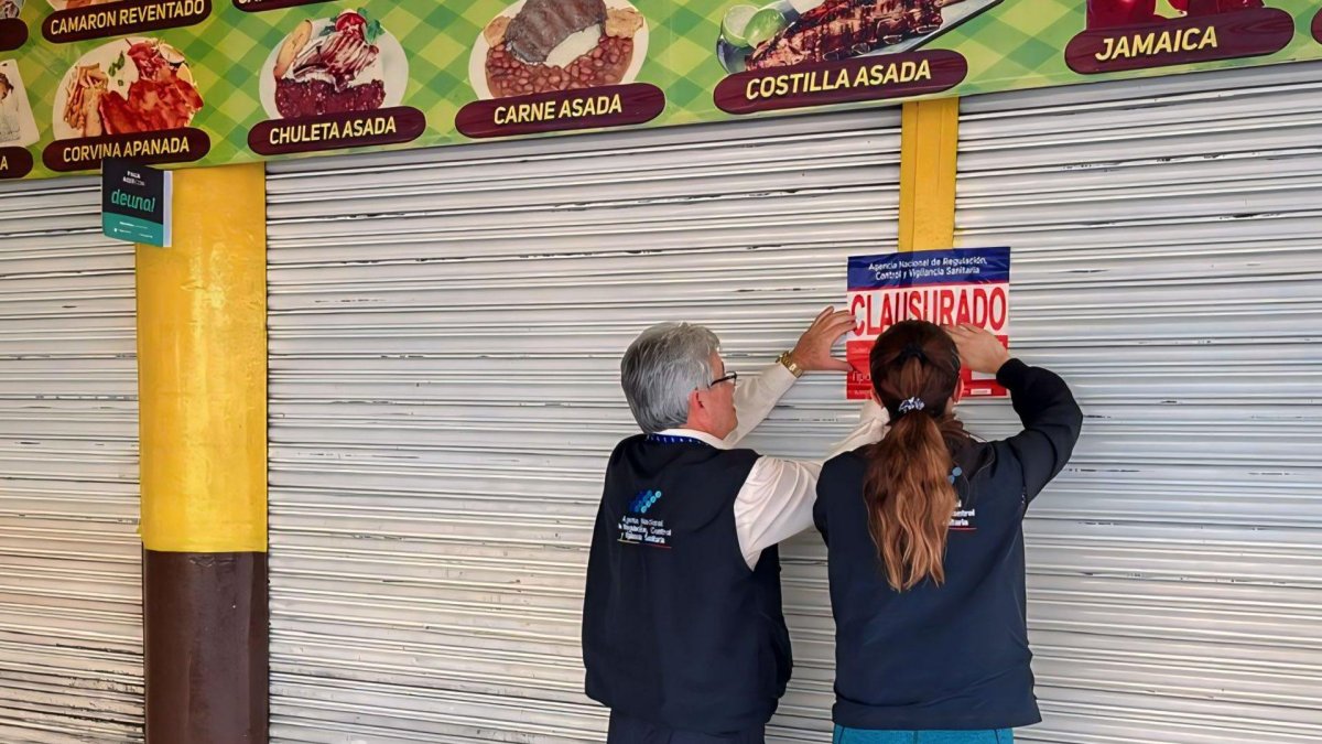 Funcionarios de Arcsa colocando la calcomanía de clausurado en uno de los cinco restaurantes