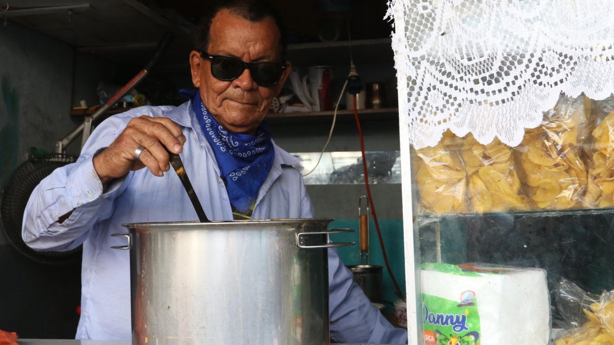 El Chino agita el caldo en la olla antes de despachar un encebollado.