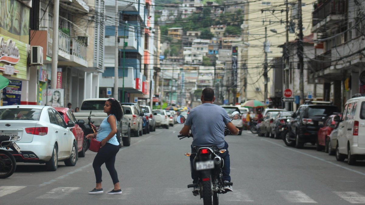 Un motociclista circula por una calle céntrica de Esmeraldas, mientras peatones y vehículos comparten la vía en medio del movimiento urbano cotidiano.