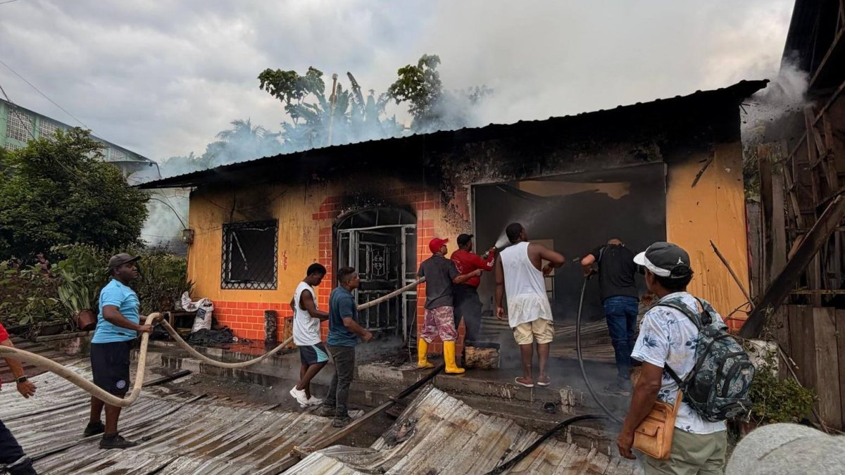 Vecinos de la parroquia Montalvo intentan sofocar las llamas con mangueras mientras un incendio consume una vivienda en Rioverde, Esmeraldas.
