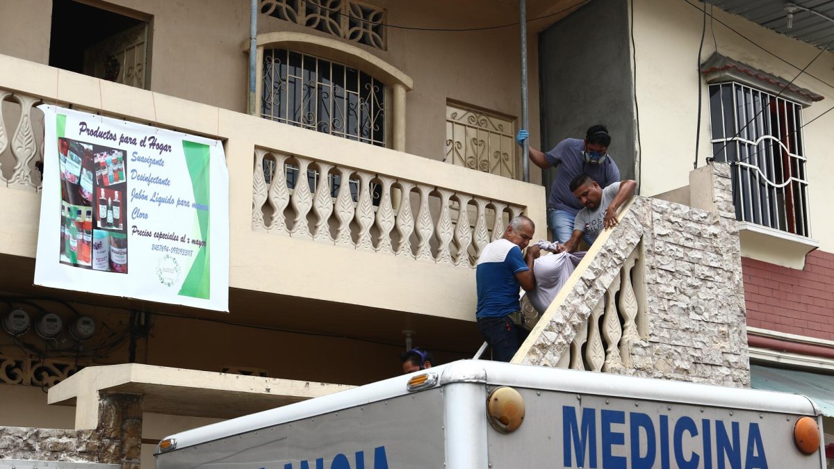 Agentes de la Policía retiran el cuerpo de la víctima envuelto en una sábana.