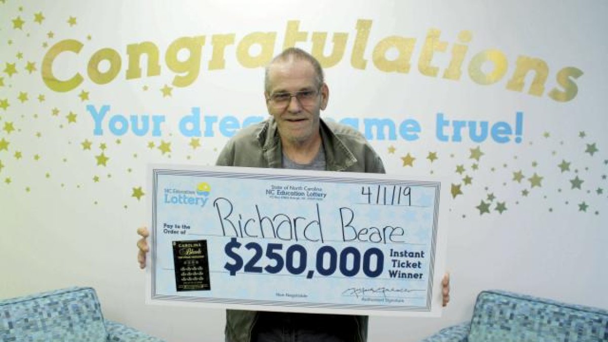 Beare sostiene un cheque tras ganar 250.000 dólares en la lotería, en Charlotte, Carolina del Norte