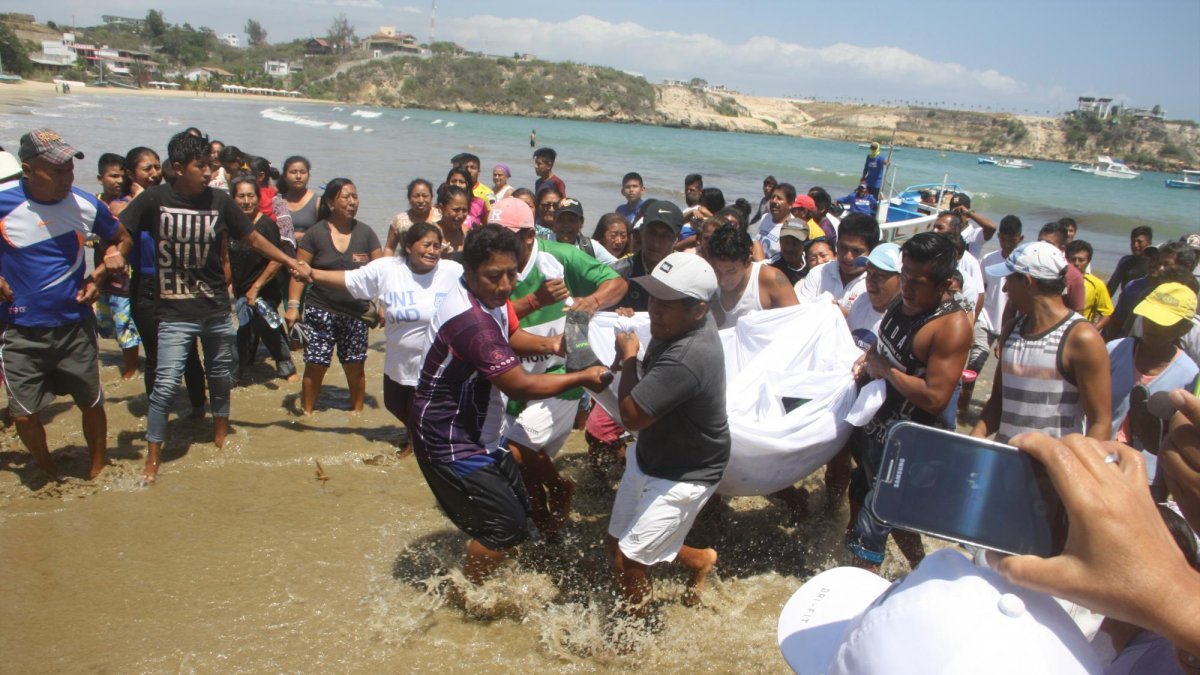 El cuerpo del pescador Álex Rodríguez es trasladado por compañeros de faena hasta la playa de Ayangue.