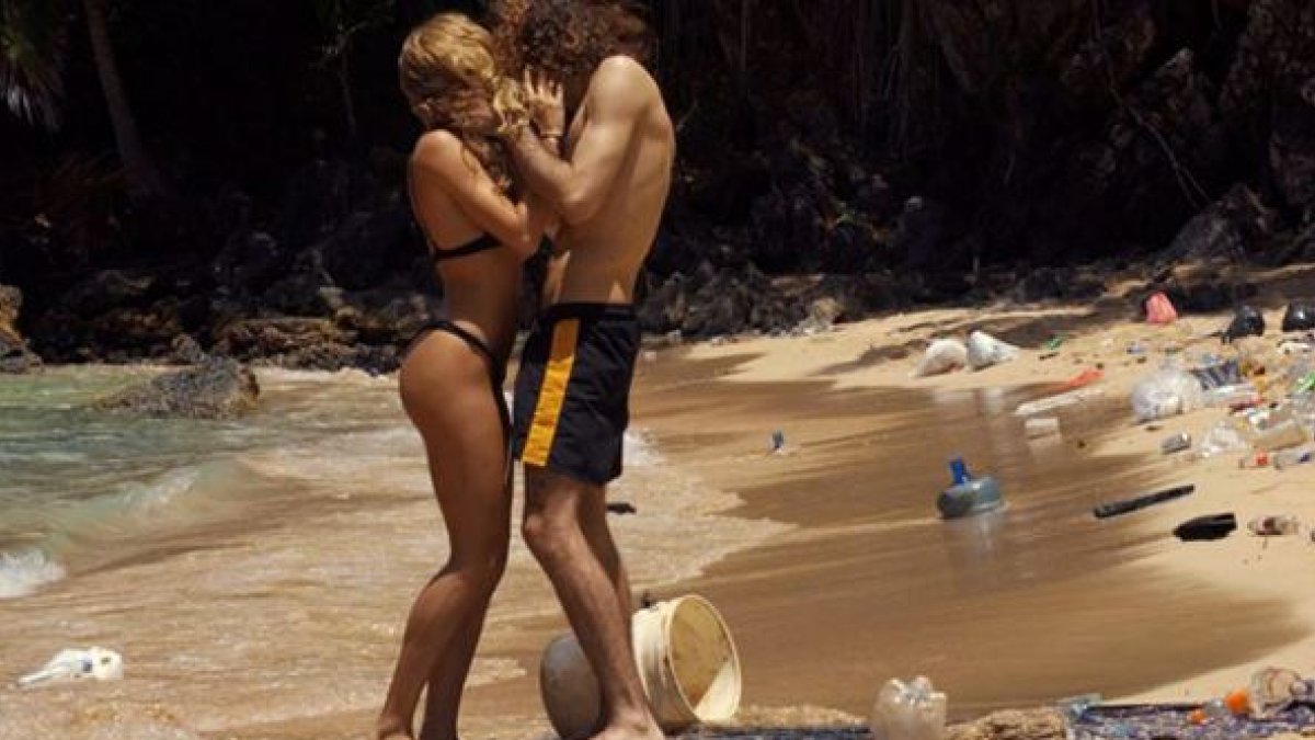 Pareja protagonista en medio la playa llena de desechos