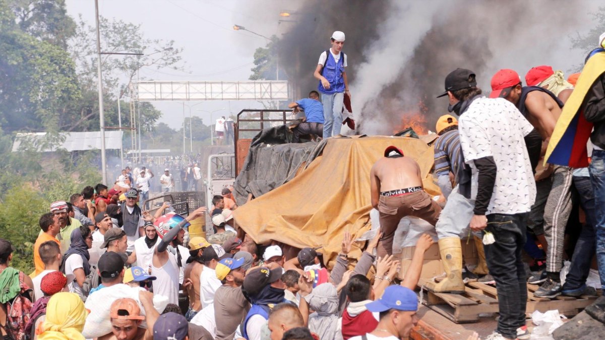 Personas intentan sacar parte de la ayuda humanitaria que se encuentra un camión que fue quemado, este sábado, en Ureña (Venezuela).