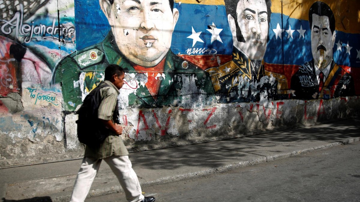 Un hombre camina por los graffiti del héroe revolucionario sudamericano Simón Bolívar, el fallecido presidente de Venezuela, Hugo Chávez, y el presidente de Venezuela, Nicolás Maduro, en Caracas.