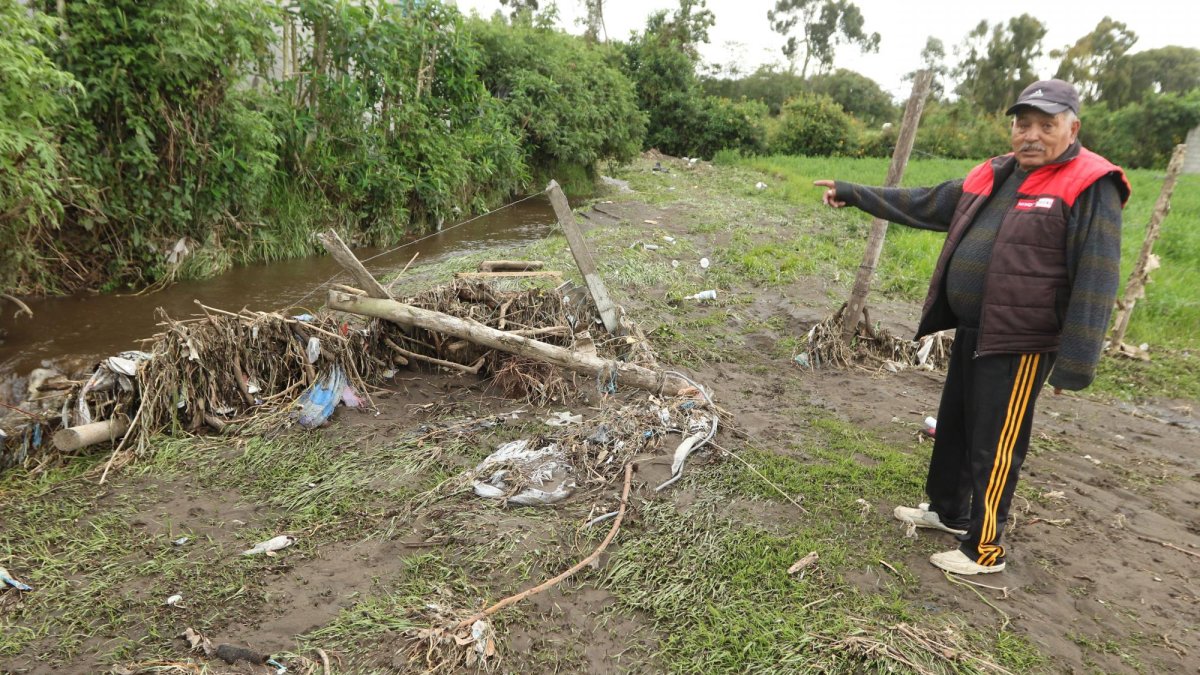 Ángel Constante muestra la crecida de la acequia cercana a su casa, además de la basura que lleva a su paso.