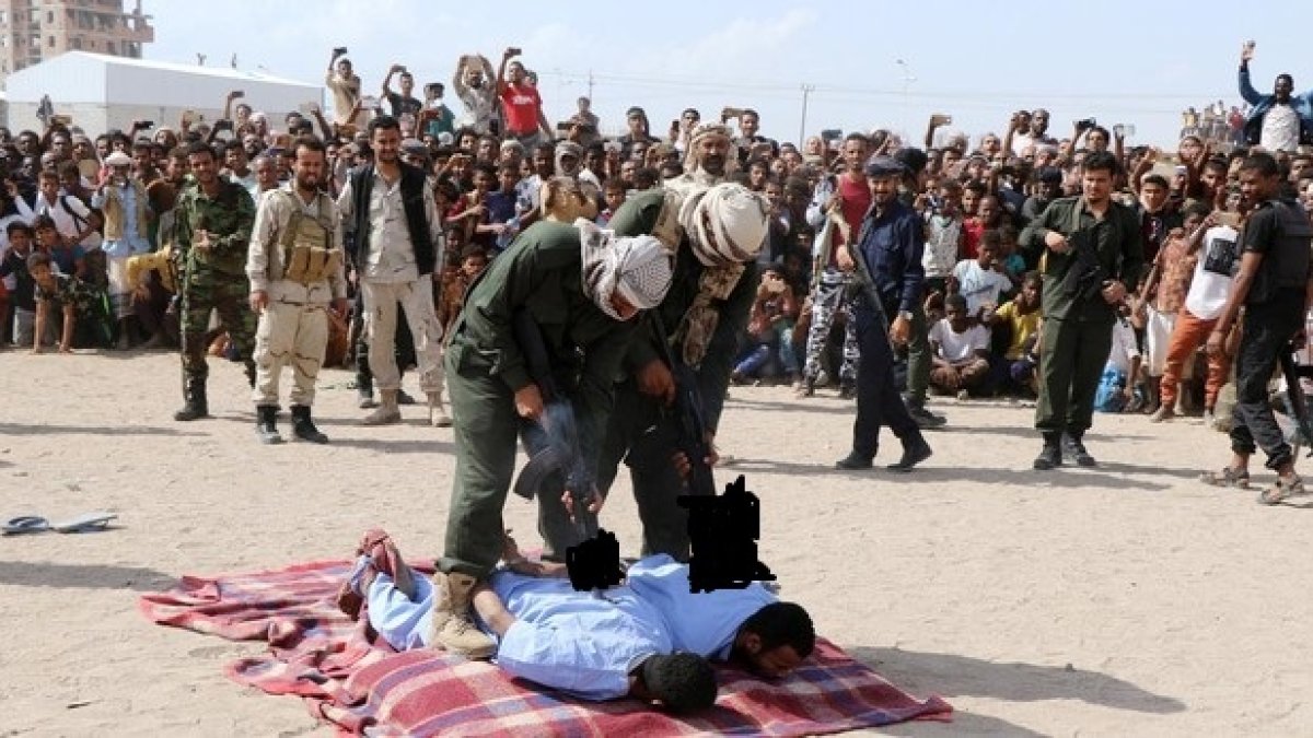 Los oficiales colocan sus AK-47 sobre las espaldas de los ajusticiados, para cumplir con su sentencia.