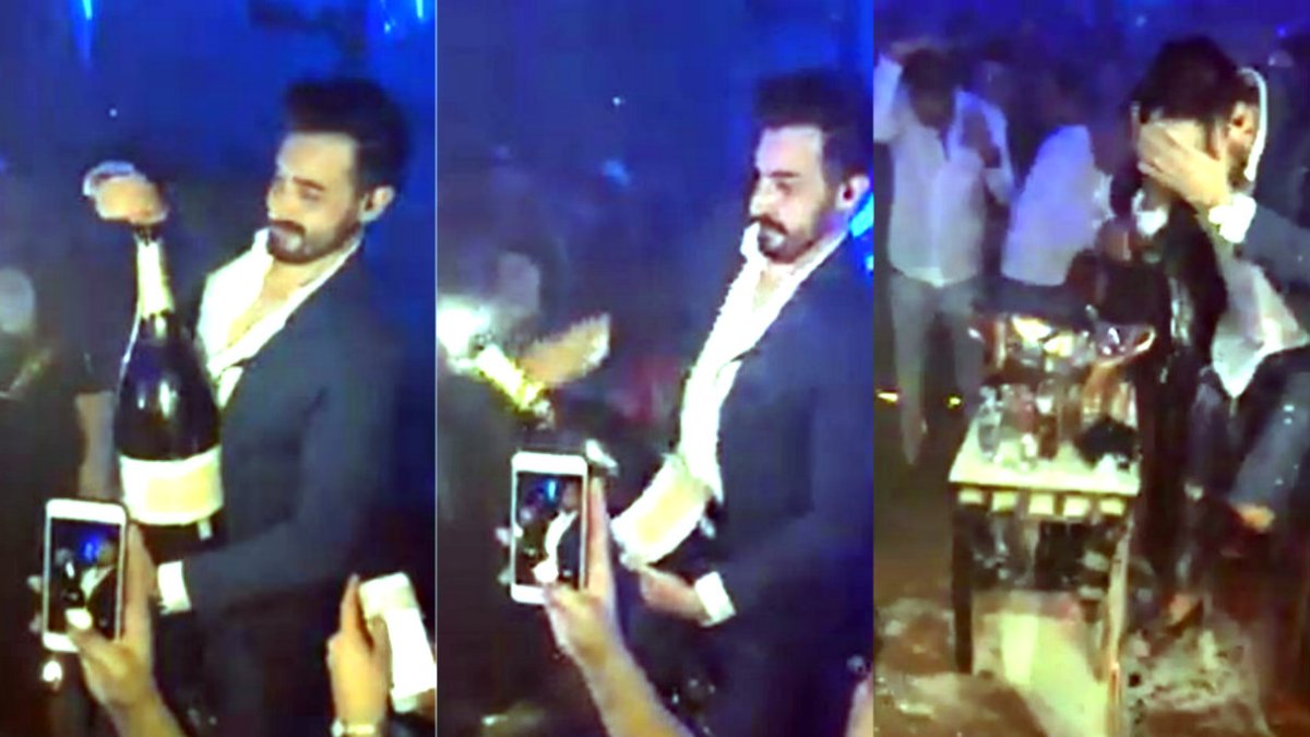 Momento en el que al hombre se le cae la botella de champagne al intentar abrirla.