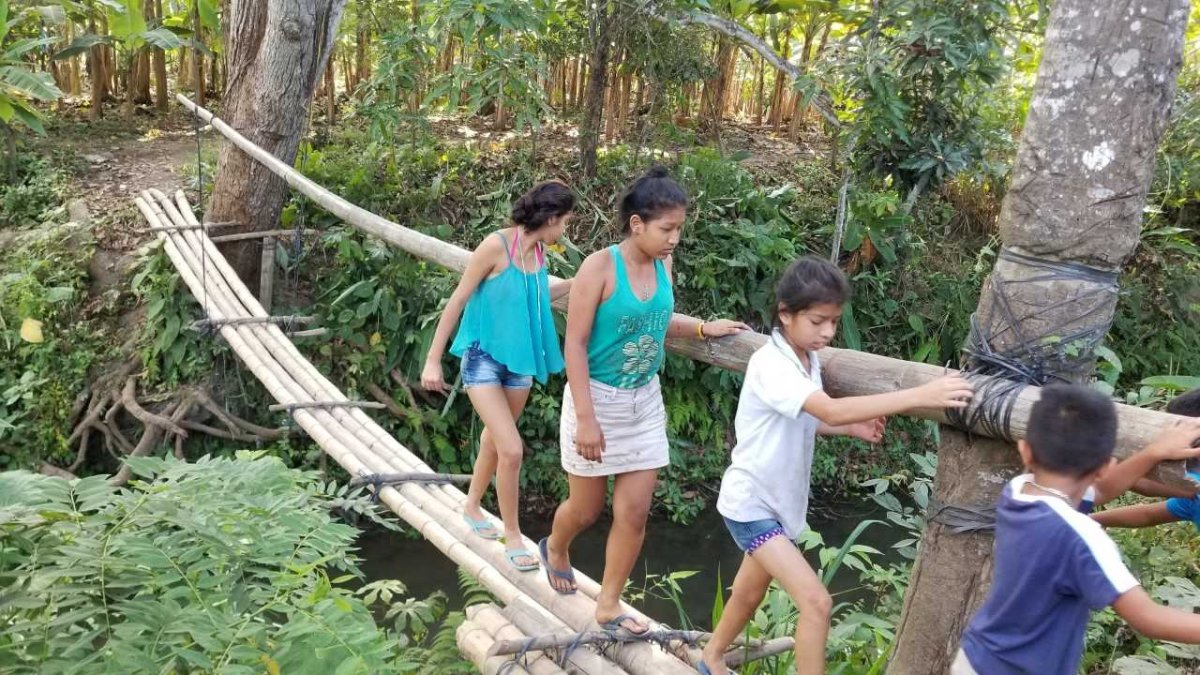 Niños cruzando el puente de caña.