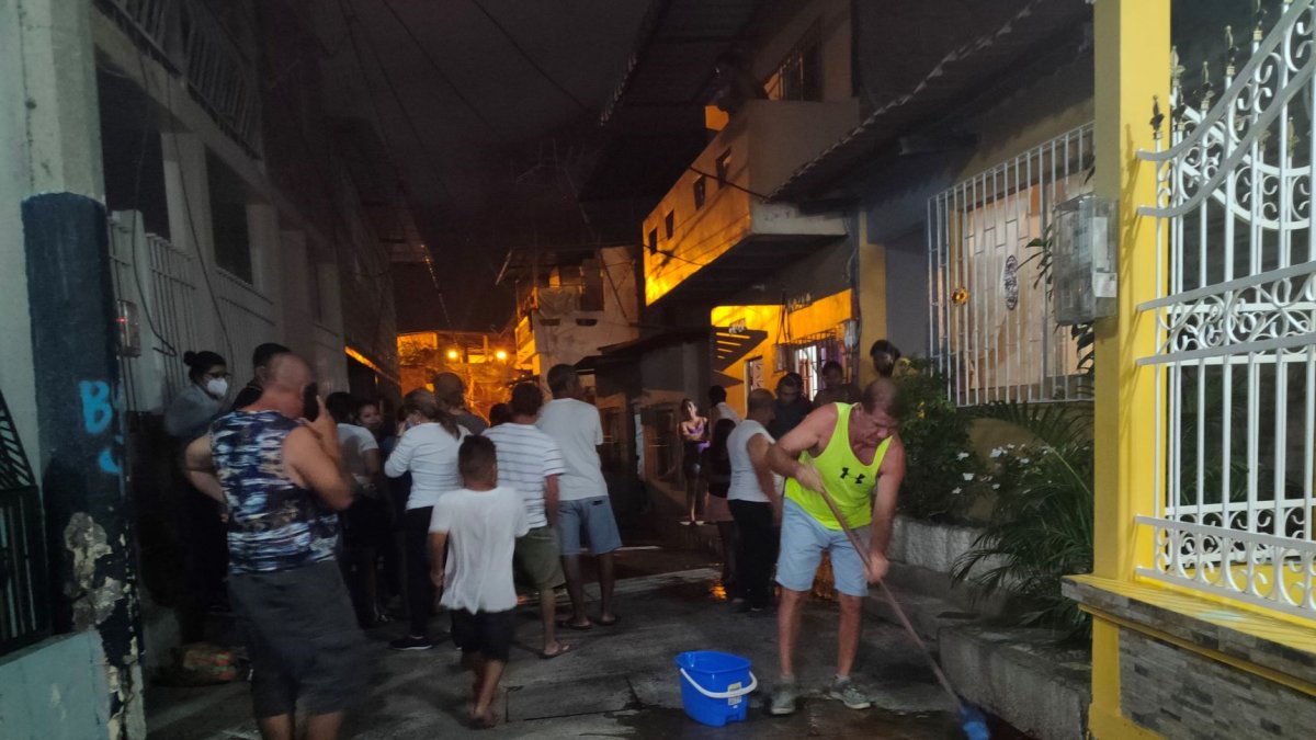 Un vecino del callejón Santa Ana, en Manta, trata de limpiar con agua y detergente el charco de sangre que quedó de la víctima.