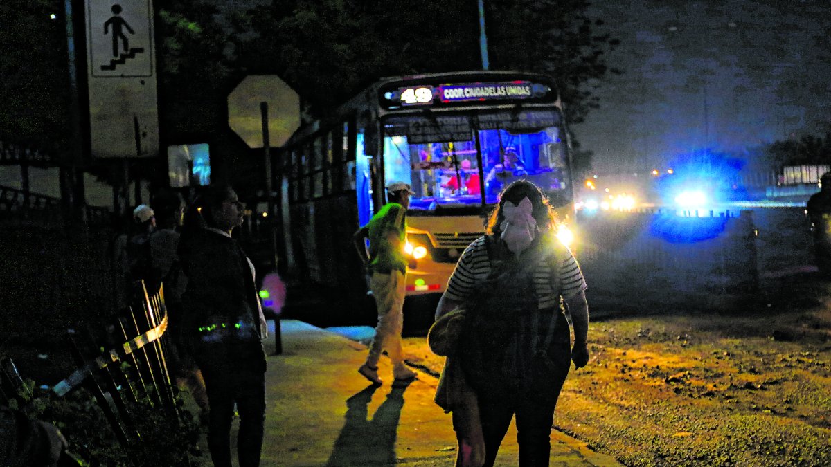 Los pasajeros esperan los buses en una oscuridad tenebrosa.
