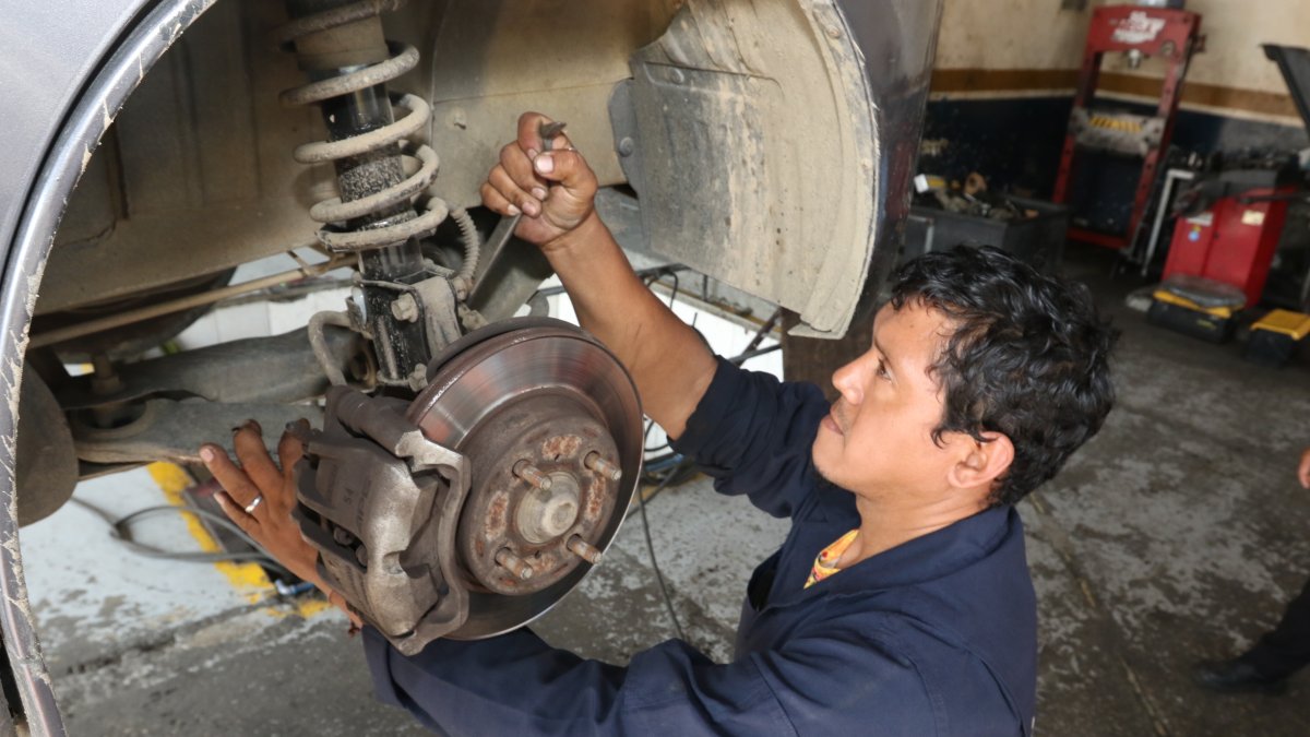 Mecánico revisa el estado de los amortiguadores del automóvil de uno de sus clientes.