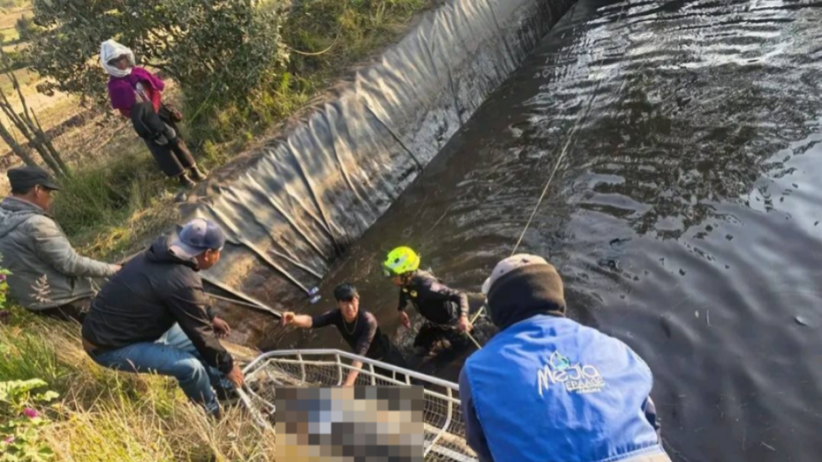 Bomberos locales mientras sacan el cuerpo de un menor de un reservorio en Guamote.