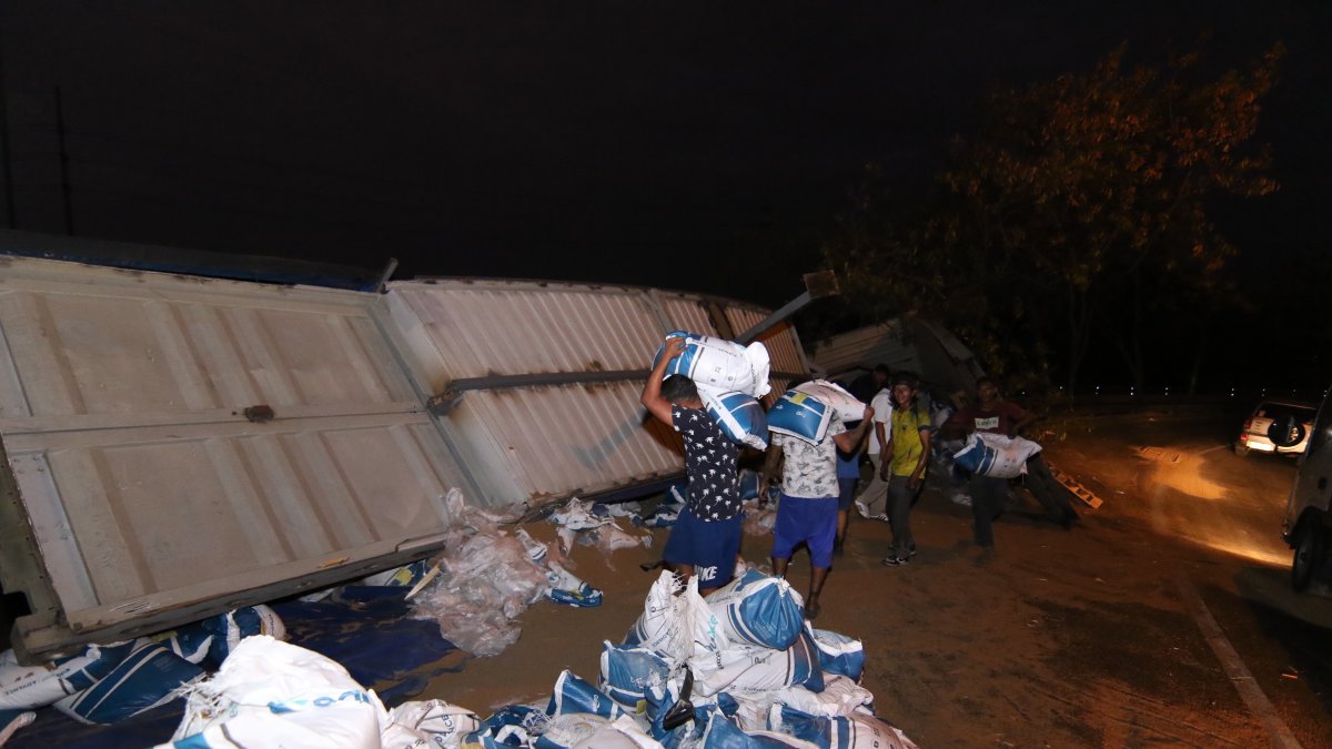 Trabajadores descargan sacos de alimento para camarón del tráiler siniestrado.
