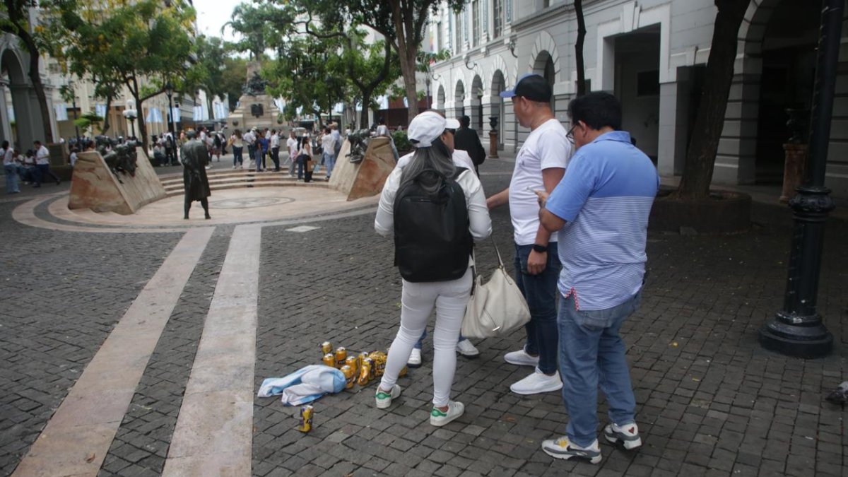 Asistentes a la marcha por Aquiles Álvarez junto a desechos de cerveza en el centro de Guayaquil.