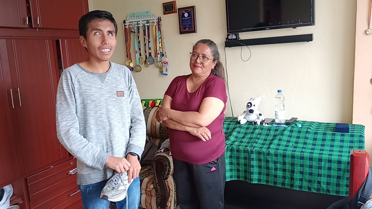 Bryan junto a su madre, Patricia Bazurto, mientras sostiene uno de los zapatos de competencia que compró hace cinco años con sus propios ahorros.