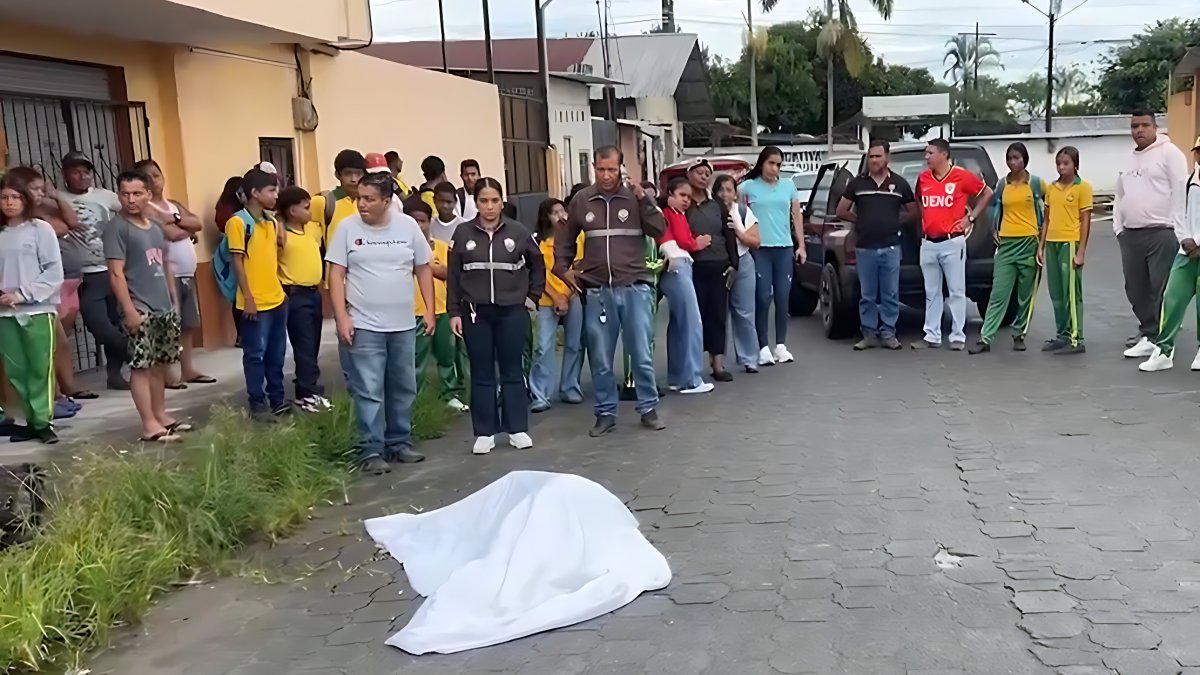Estudiantes y docentes rodean el cuerpo de la profesora Diana Alcívar, asesinada a pocos metros del colegio donde laboraba.