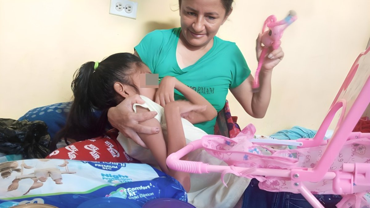 Con su hija en brazos, Mayra muestra las leches y otros insumos que compró gracias a los lectores.